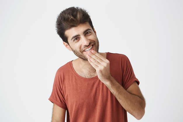 Atractivo joven de raza caucásica de aspecto agradable. Alegre y sonriente, demostrando que sus dientes blancos tienen buen humor después de recibir buenas noticias