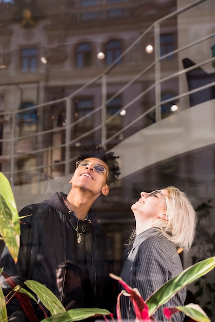 Un atractivo joven sonriente pareja llevaba gafas mirando hacia arriba