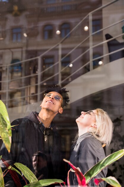 Un atractivo joven sonriente pareja llevaba gafas mirando hacia arriba