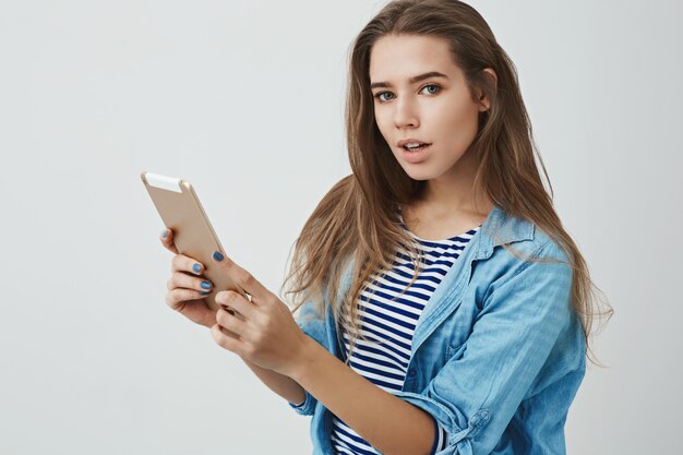 Atractivo moderno milenario joven mujer descarada de moda con tableta digital