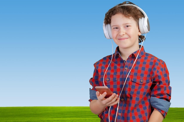 Atractivo niño está escuchando música con auriculares.