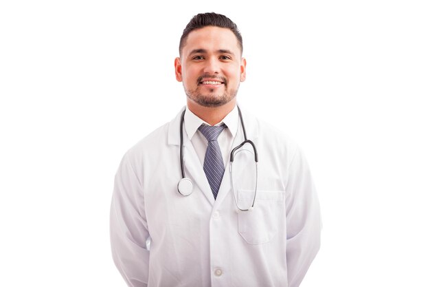 Atractivo nutriólogo masculino joven en una bata de laboratorio sonriendo contra un fondo blanco.
