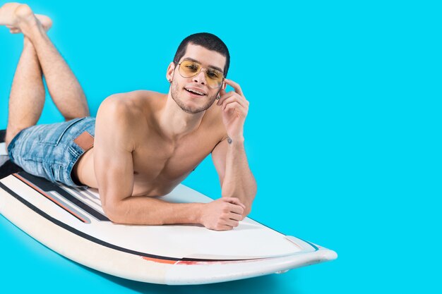 Atractivo surfista acostado en el tablero