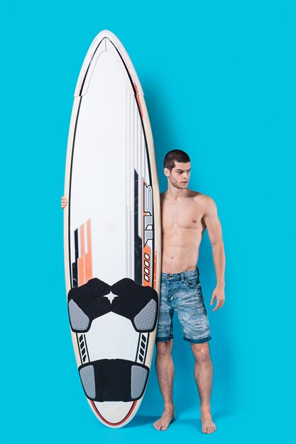 Atractivo surfista sosteniendo una tabla de surf