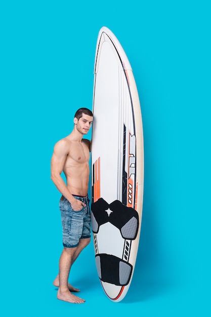 Atractivo surfista sosteniendo una tabla de surf