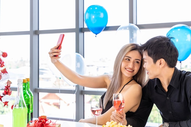 Atractivos hombres y mujeres jóvenes celebran la Navidad y el Año Nuevo en la fiesta de la oficina hombre y mujer tomando selfie juntos