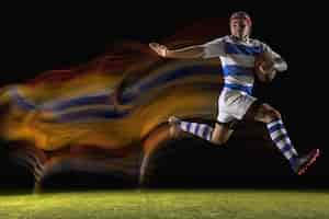Foto gratuita atrapado en un momento importante. un hombre caucásico jugando al rugby en el estadio con luz mixta.