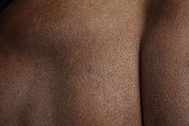 Atrás. Textura detallada de la piel humana. Primer plano del cuerpo masculino joven afroamericano. Concepto de cuidado de la piel, cuidado corporal, salud, higiene y medicina. Se ve bella y bien cuidada. Dermatología.