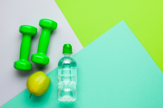 Atributos deportivos planos con botella de agua y manzana