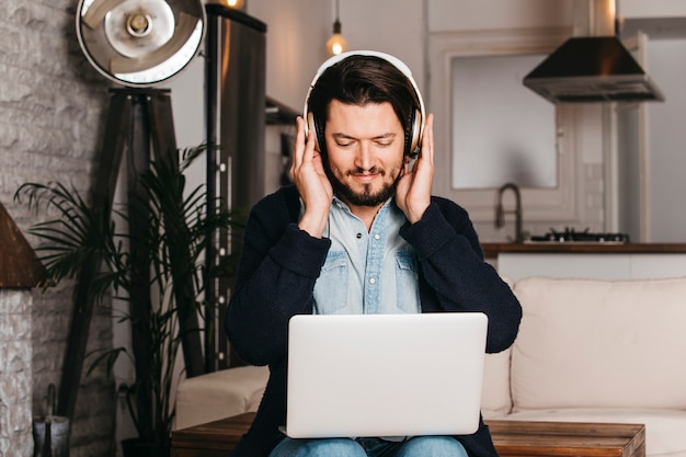 Auricular que lleva del hombre que mira la tableta digital que se sienta en la cocina