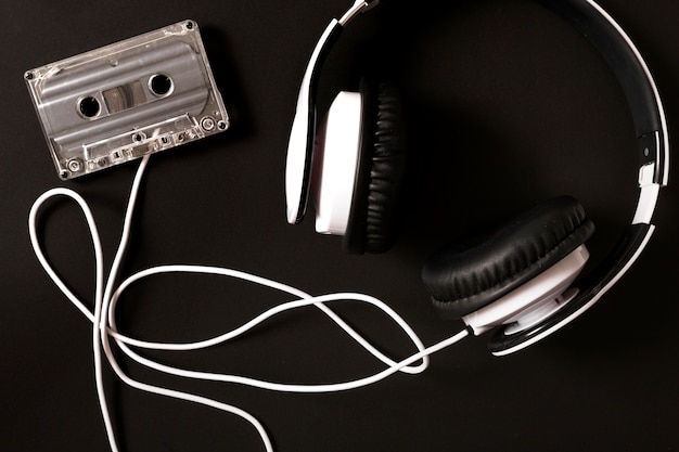 Auriculares conectados a cassette transparente sobre fondo negro