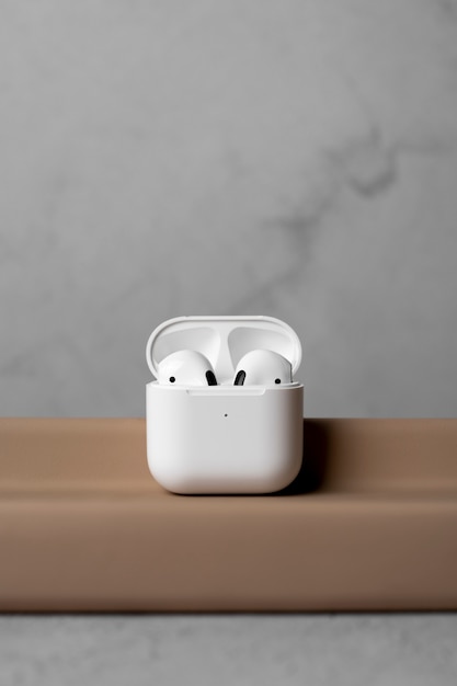 Foto gratuita auriculares inalámbricos modernos con estuche y fondo concreto simple