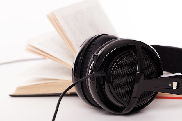 Auriculares y libro sobre un fondo blanco.