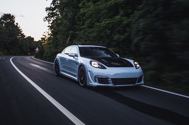 Un auto deportivo blanco con autotuning negro conduciendo por el bosque.