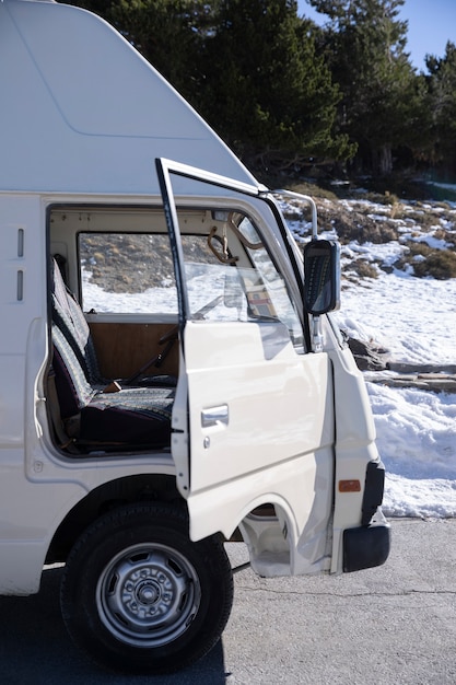 Autocaravana con una puerta abierta en el camino a través del bosque durante el viaje de invierno