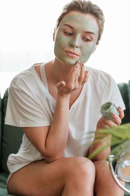 Foto gratuita autocuidado en casa con mujer aplicando mascarilla facial