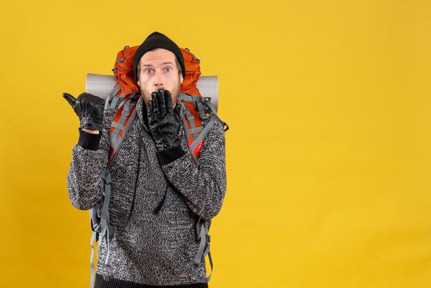 Autoestopista masculino conmocionado con guantes de cuero y mochila