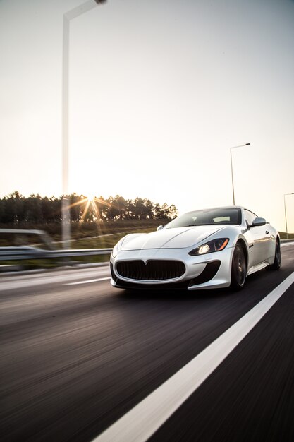 Un automóvil deportivo de color metálico plateado que conduce a alta velocidad en la carretera.