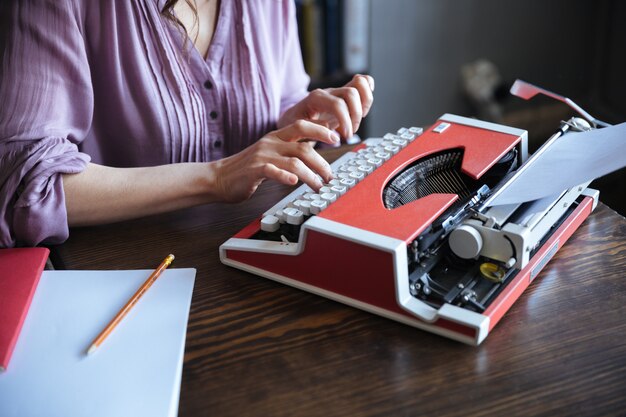 Autora sentada en la mesa y escribiendo en máquina de escribir en el interior
