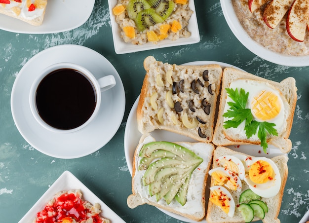 Avena con frutas, canela, mermelada, sándwich, café en platos