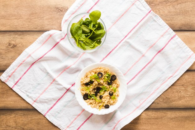 Avena saludable adornada con hojas de albahaca y oliva para el desayuno en mesa de madera