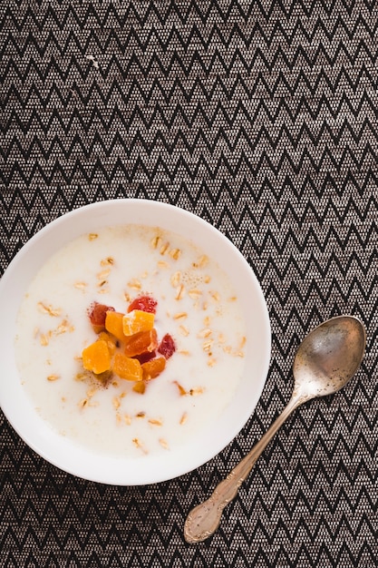 Foto gratuita avena en el tazón con cuchara vieja en mantel individual