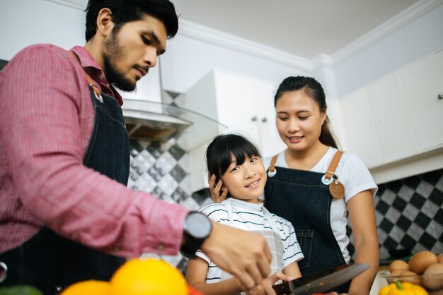 Ayuda feliz de la familia que cocina la comida junta en cocina en casa.