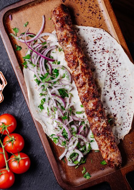 Azerbaiyán lule kebab en pan lavash con ensalada de cebolla verde.