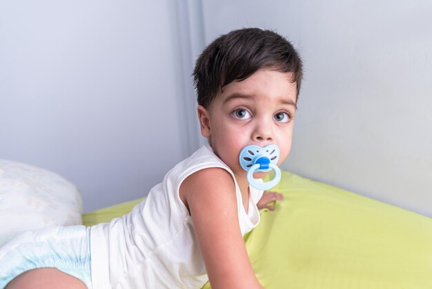 Baby Boy en camiseta blanca acostado en la cama