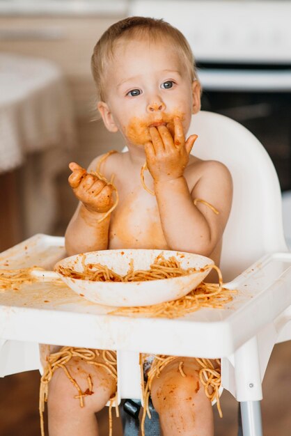 Baby Boy lamiendo sus dedos después de comer pasta