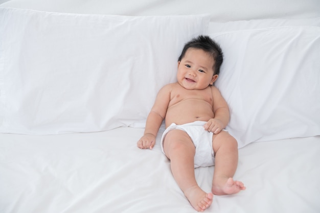 Baby Boy vistiendo pañales en dormitorio soleado blanco