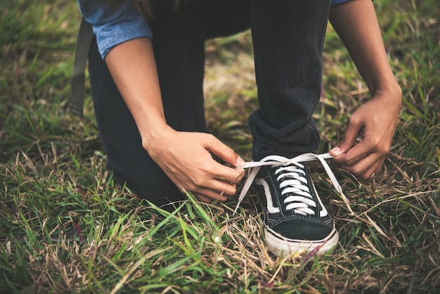 Backpacker de la mujer atarse los cordones pequeños mientras van de excursión al bosque.