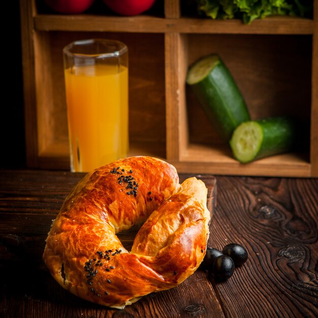 bagel con aceitunas y jugo de naranja y pepinos en la mesa