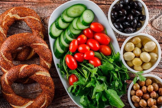 Bagel turco en una olla con ensalada, encurtidos en tazones vista superior sobre una superficie de madera