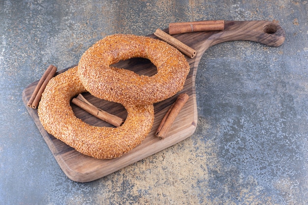 Bagels y palitos de canela sobre una tabla de madera sobre la superficie de mármol