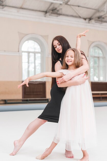 Bailarín de ballet abrazando a sonriente chica linda practicando en estudio de danza