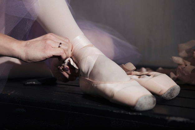 Foto gratuita bailarín de ballet de la cosecha que ata los zapatos del pointe