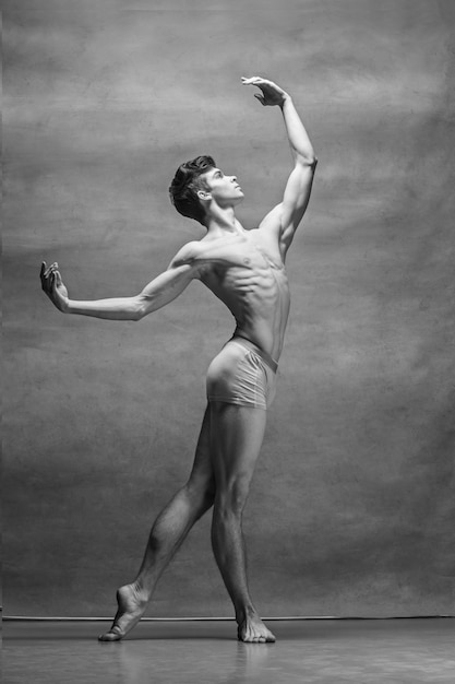 El bailarín de ballet masculino posando sobre gris