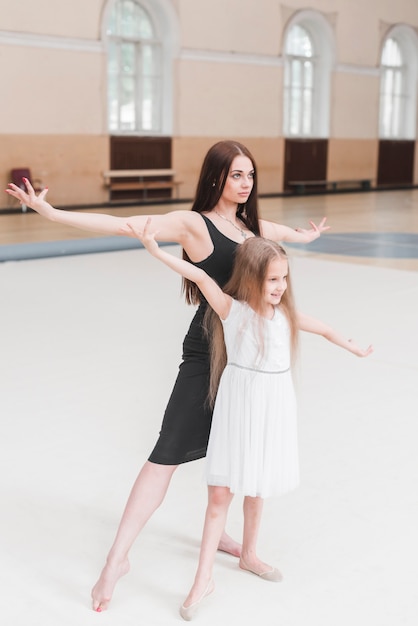 Foto gratuita bailarín de ballet y niña practicando en estudio de danza