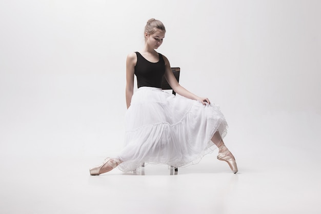 Bailarina adolescente en falda blanca posando en la silla