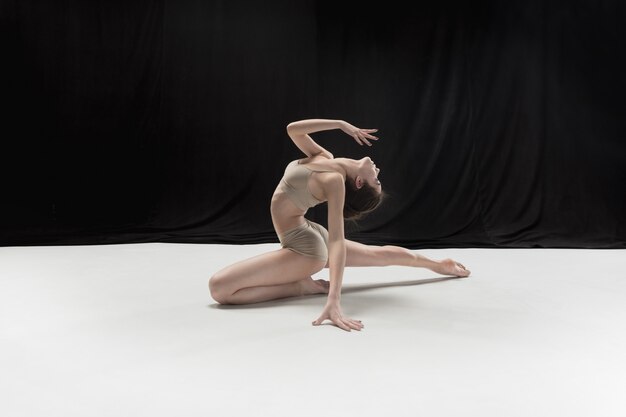 Bailarina adolescente joven en suelo blanco.