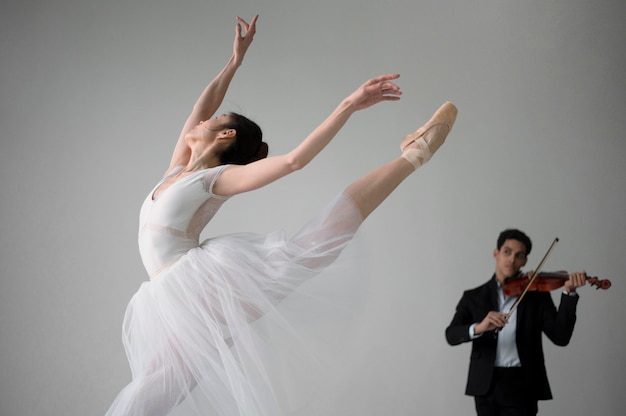 Bailarina bailando en tutú y músico tocando el violín