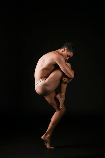 Bailarina de ballet abrazando apasionadamente la rodilla