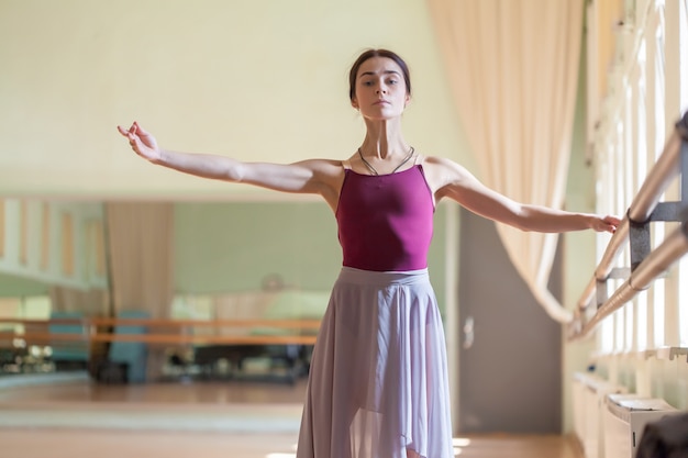 Bailarina de ballet clásico posando en barre en sala de ensayo