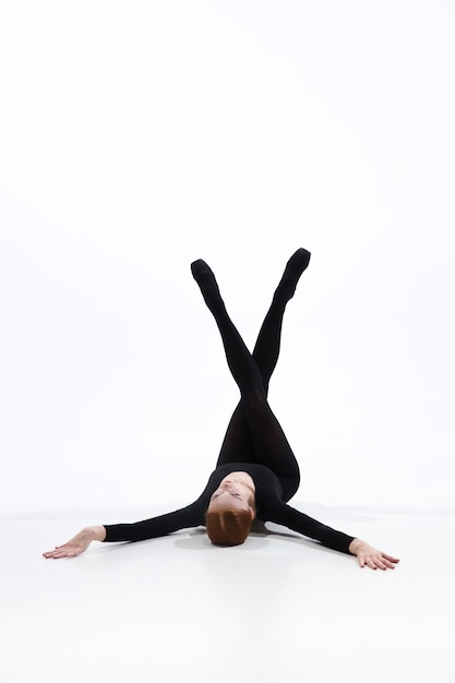 Bailarina de ballet joven y elegante en estilo negro mínimo aislado sobre fondo blanco de estudio.