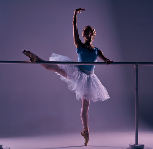 Bailarina clásica posando en la barra de ballet