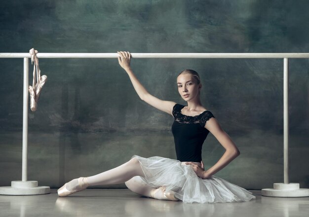 La bailarina clásica posando en la barra de ballet.