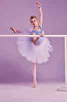 Foto gratuita bailarina clásica posando en la barra de ballet