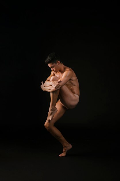 Bailarina desnuda abrazando la rodilla