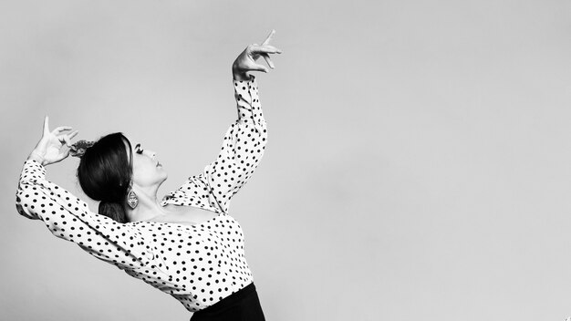 Bailarina flamenca en blanco y negro agachándose con espacio de copia